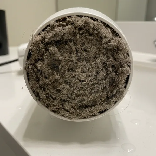 A hair dryer with visible dust, lint, and hair clogging its air intake filter and vents, illustrating a common cause of burning smell.